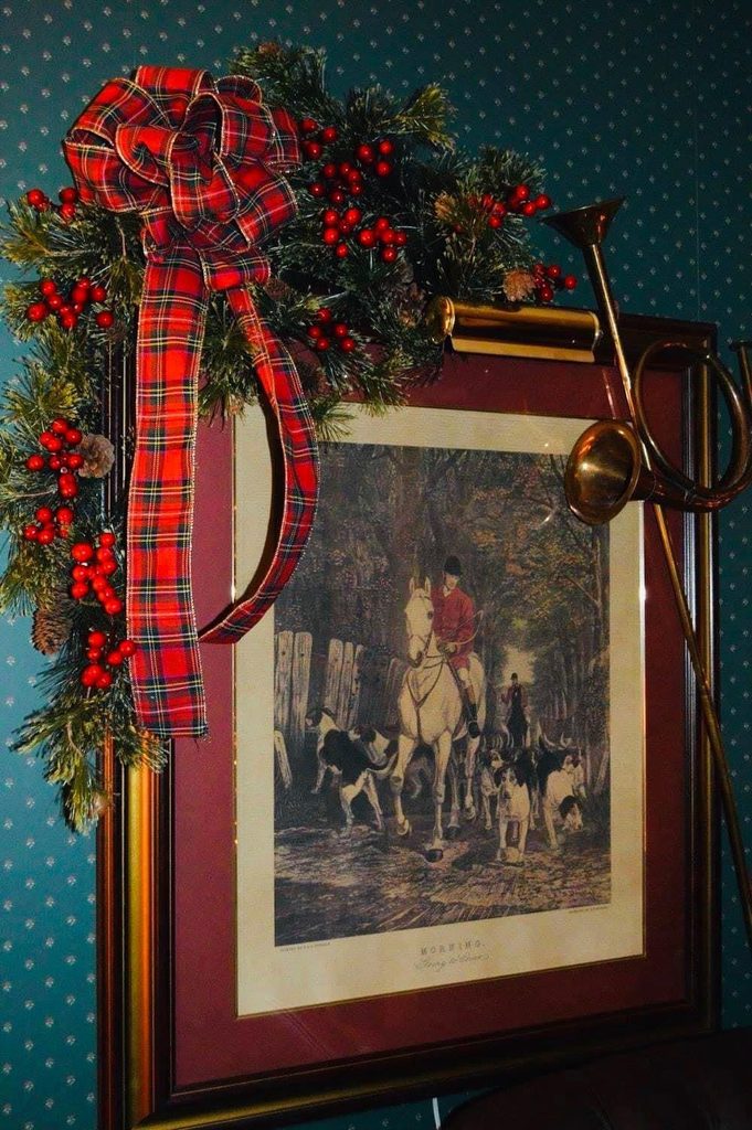 Vintage framed Christmas artwork decorated with red velvet ribbon and winter berries