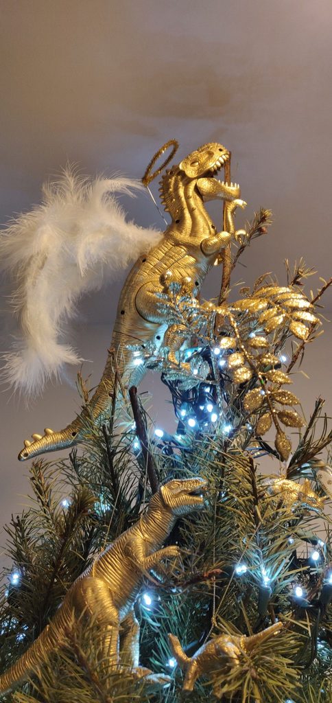Gold angel Christmas tree topper surrounded by glowing blue and warm lights