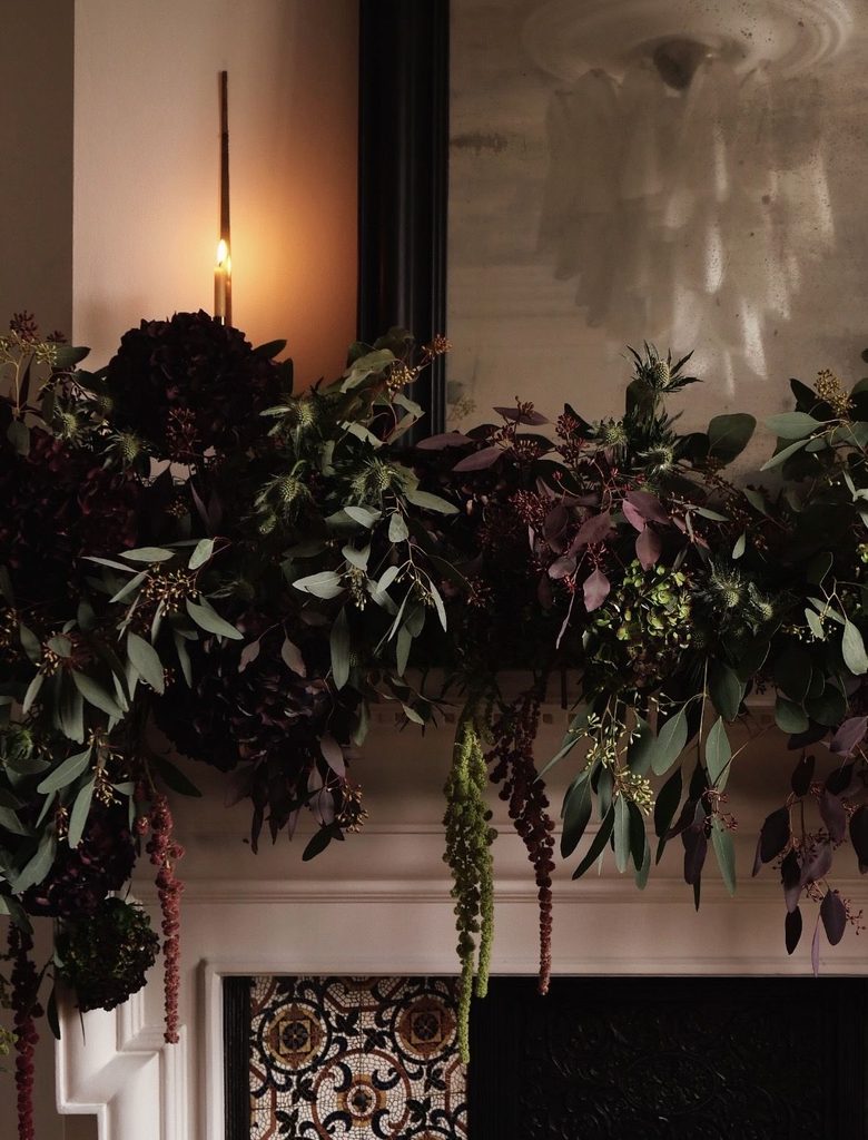 Natural evergreen garland draped loosely over a mantel with warm candlelight
